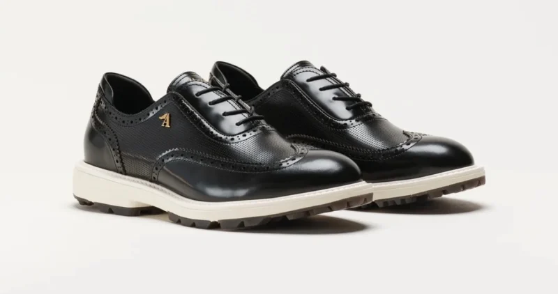 Aberdeen West AW Wingtip in black leather — brogue punching, gold A on the quarter, white midsole over a lugged sole